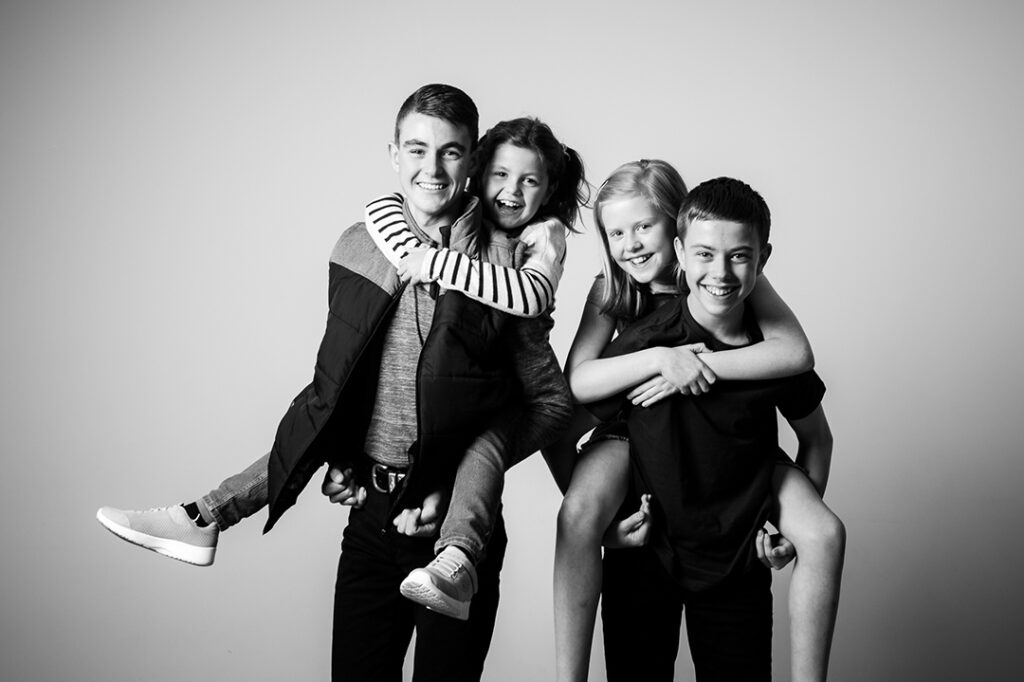 Black and white family portrait featuring grandchildren having fun at photography studio in Abergavenny